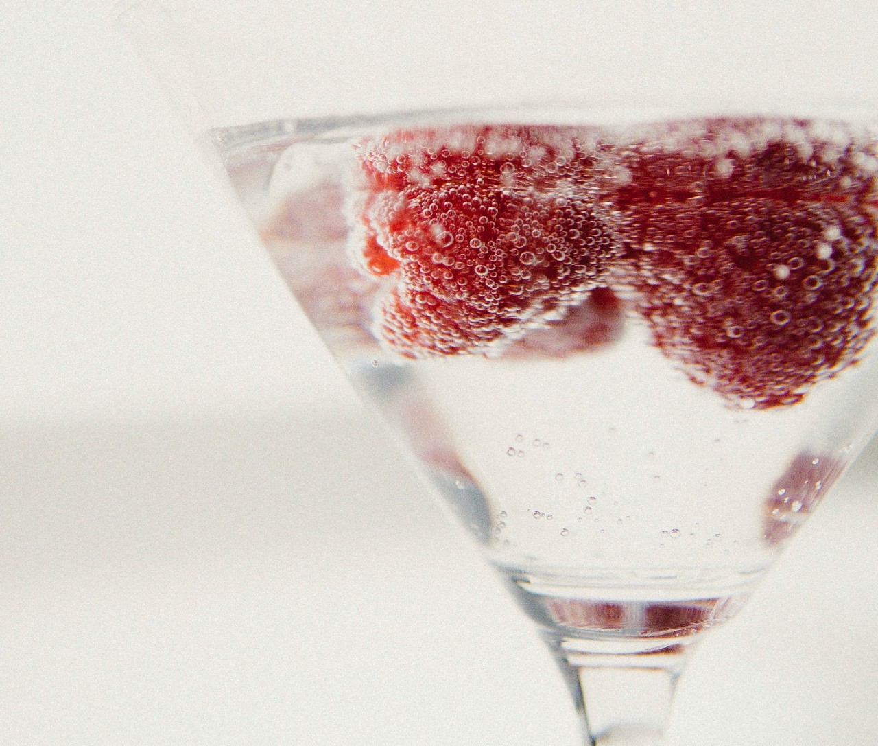 Alcoholic drink with raspberries in a wine glass