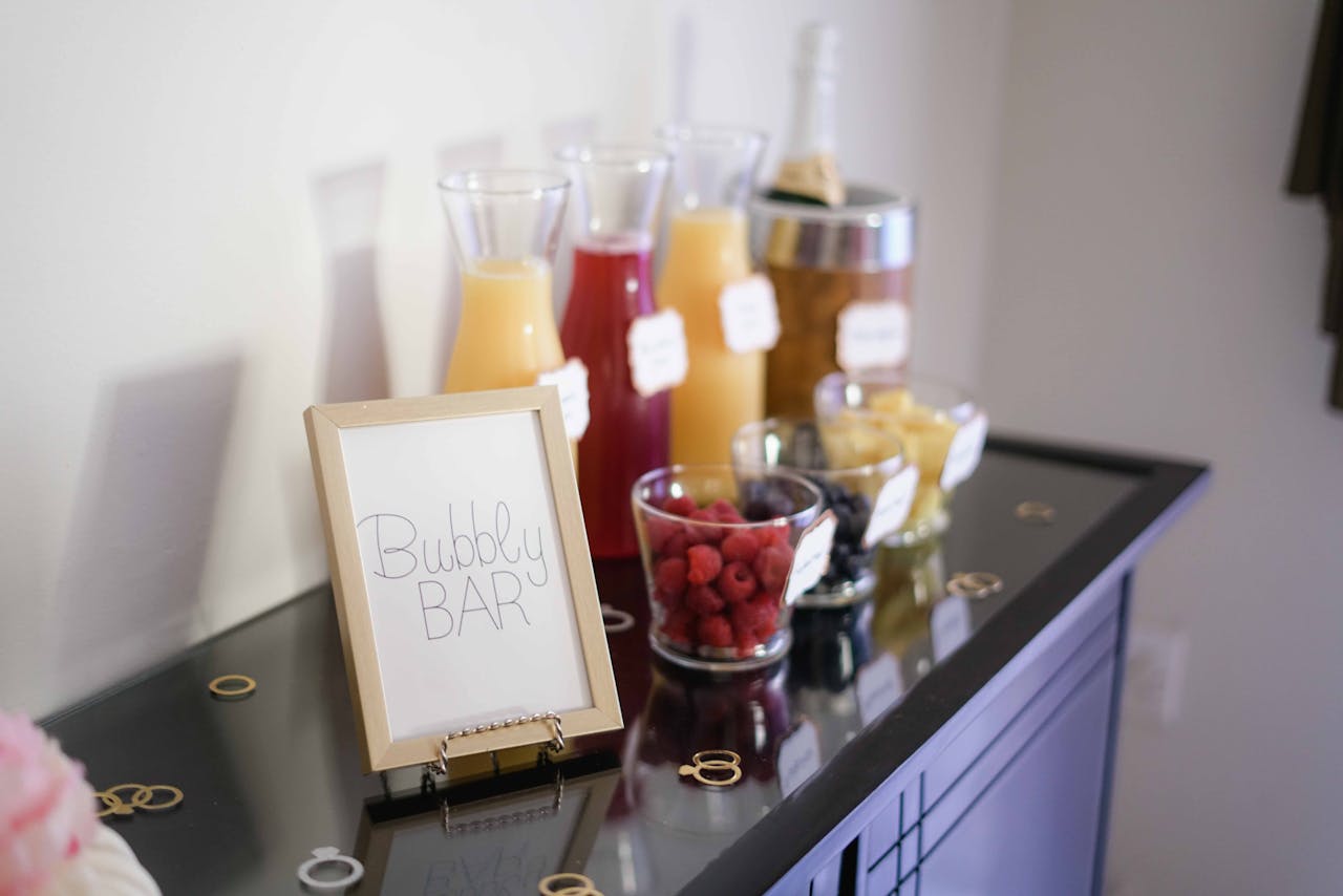 Bubbly bar table with various drinks in glasses, glass cups and a champagne bottle