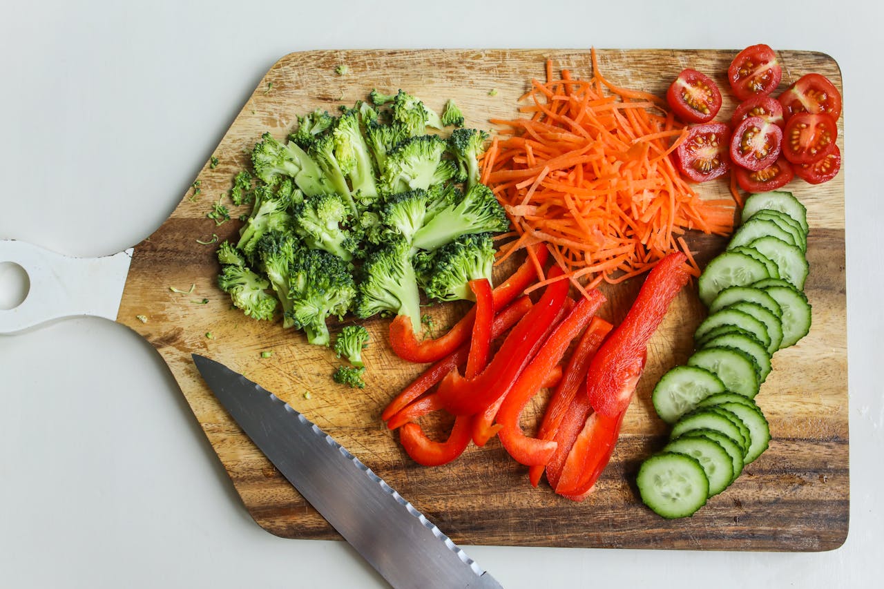 Sliced carrots, red peppers, cucumbers, carrots and tomatoes on a cutting board