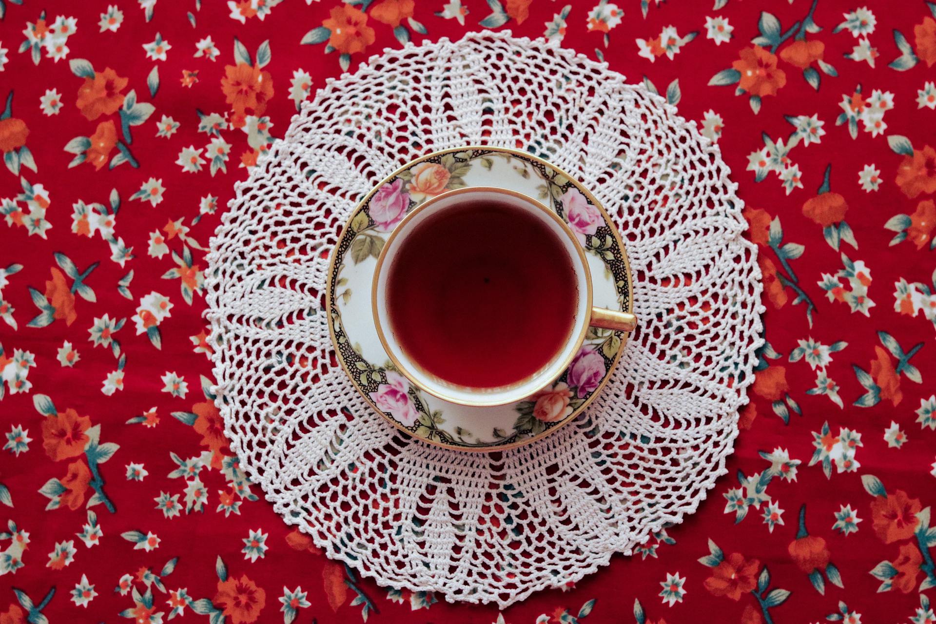 Red liquid in a teacup, both on a red mat