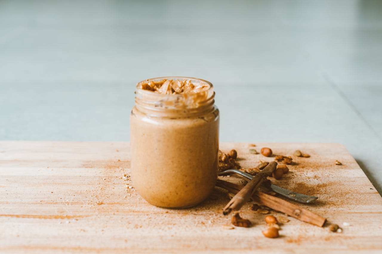 Glass Jar of Peanut Butter on Wooden Cutting Board